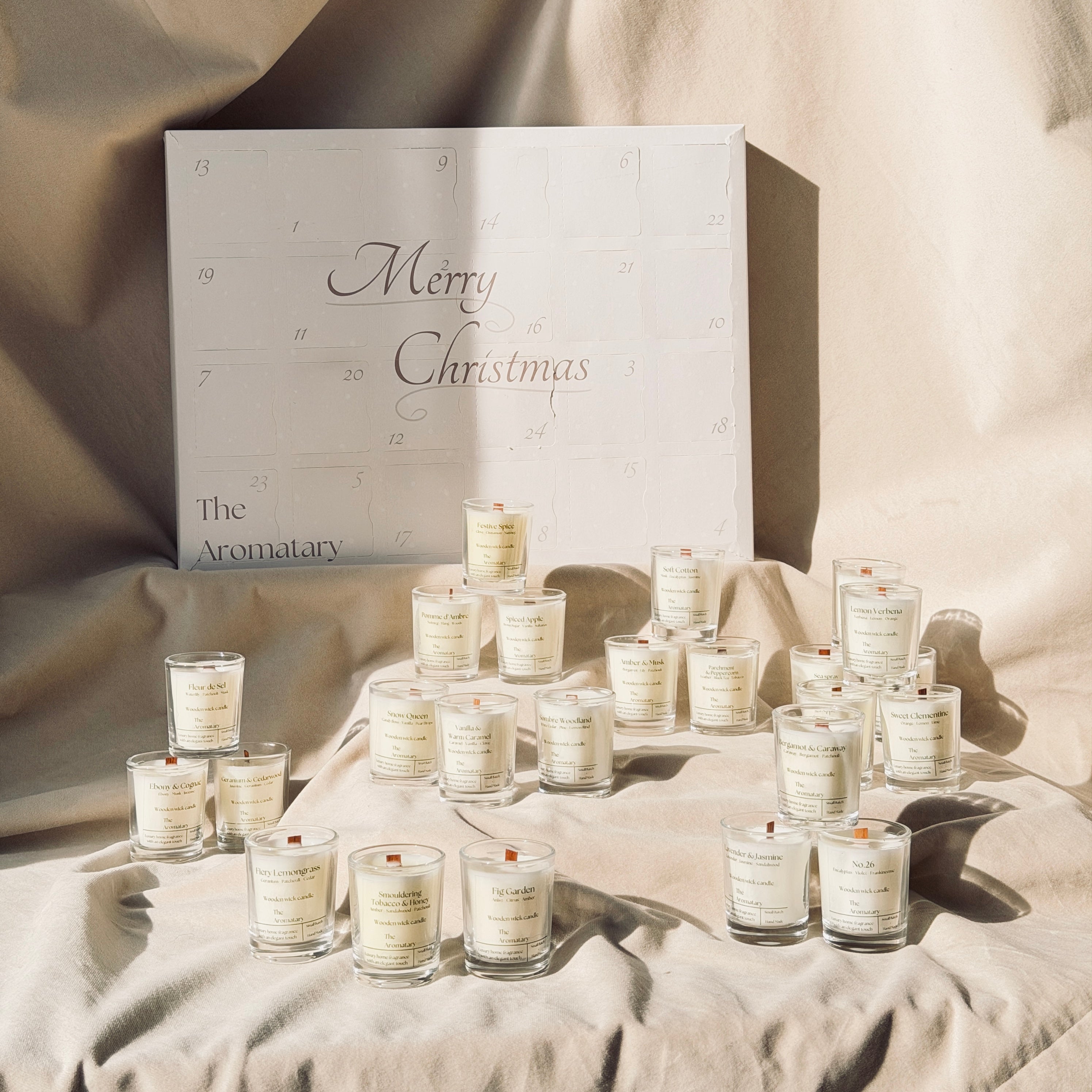 Set of candles in front of a 'Merry Christmas' box on a textured surface